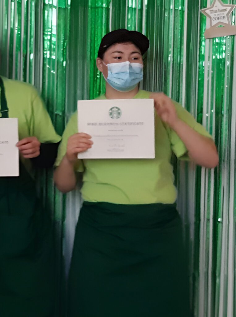 Christianna Faith hold up a certificate from starbucks