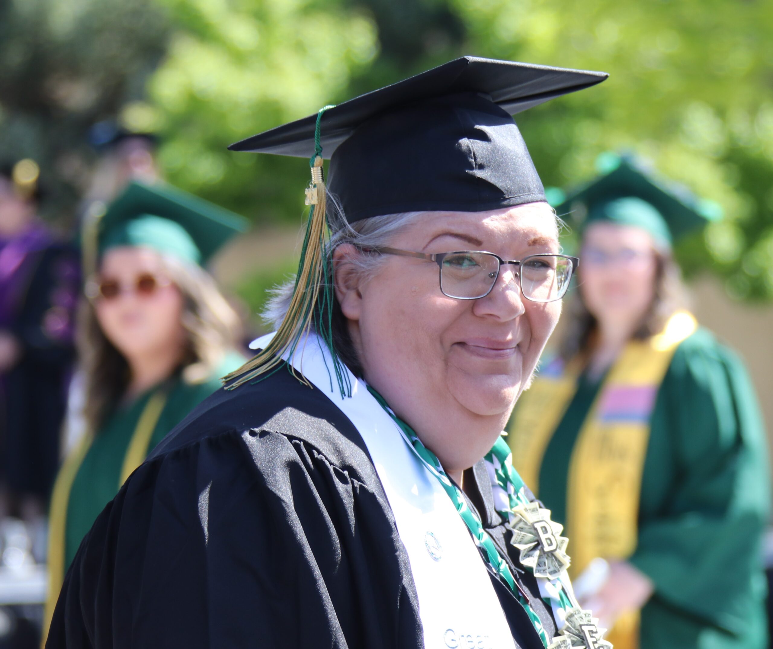 rebecca smiles wearing her cap and gown at graduation