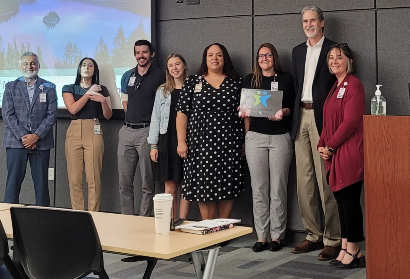 a diverse group of Renown management smile as they pose with vocational rehabilitation representatives and their plaque