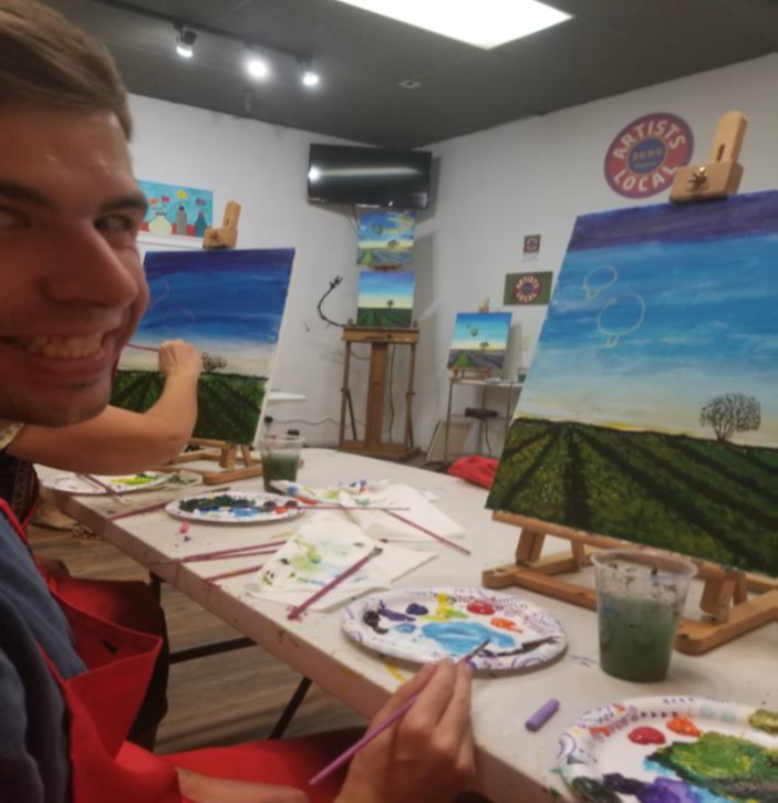 mitchell smiles in front of his landscape painting