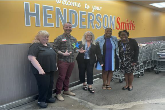 a diverse group of smith's management smile as they pose with vocational rehabilitation representatives and their plaque