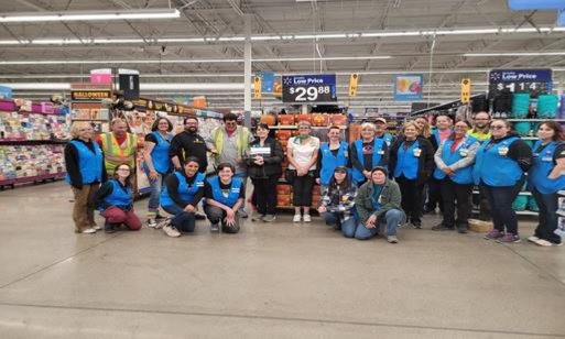 a diverse group of walmart employees smile as they pose with vocational rehabilitation representatives and their plaque