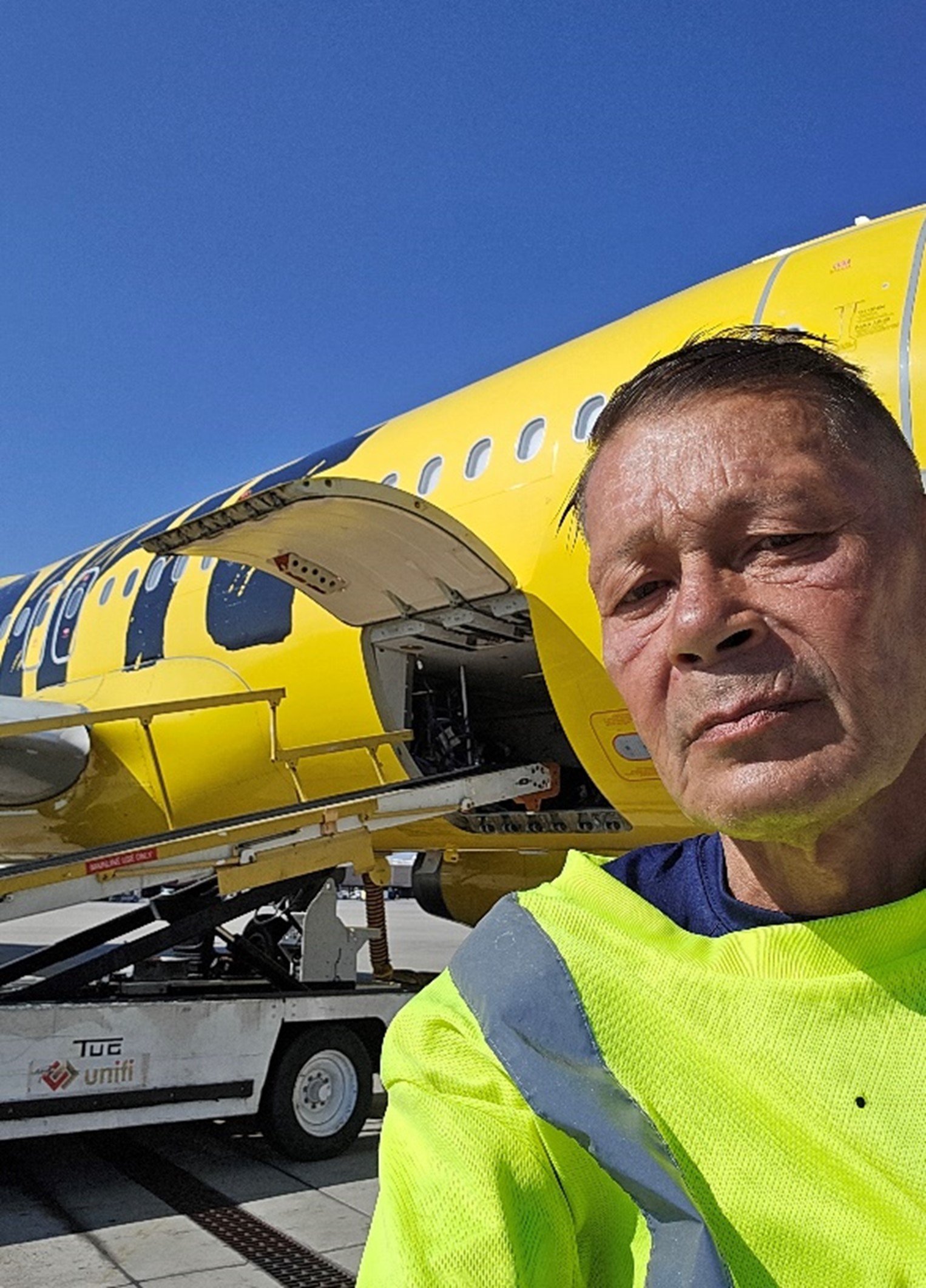 walter poses in front of a 737 with the cargo bay door open on the tarmac