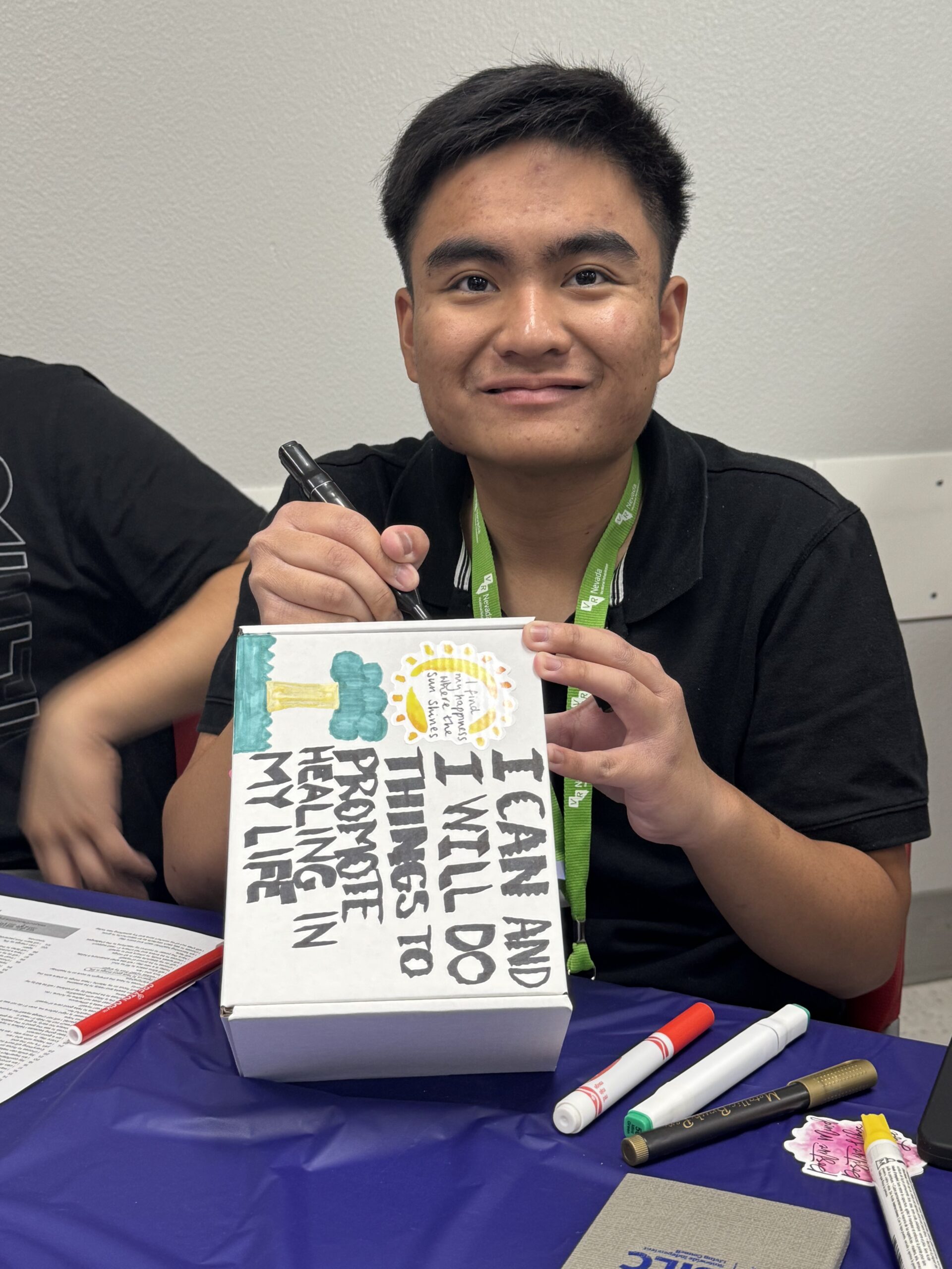 a student is writing positive affirmations on a decorated box